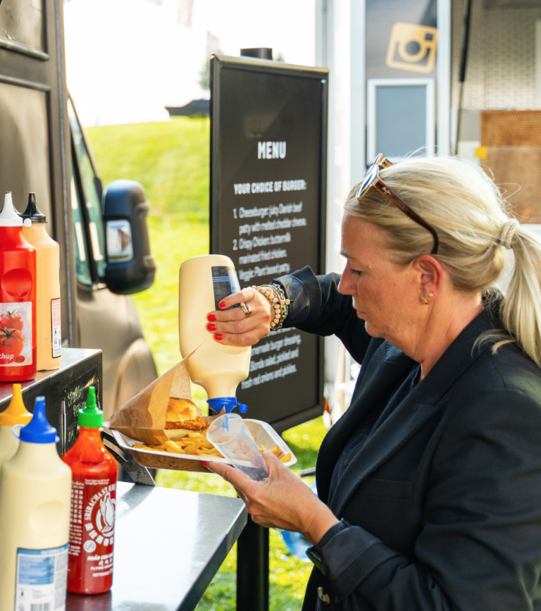 Gæst tager dressing ved menutavlen på Burger Foodtrucks vogn