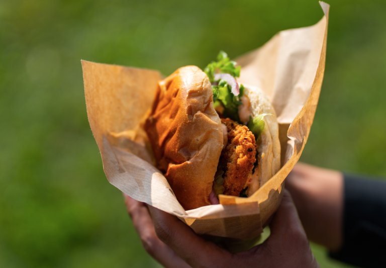 Chickenburger med salat i papir holdt ud i det grønne