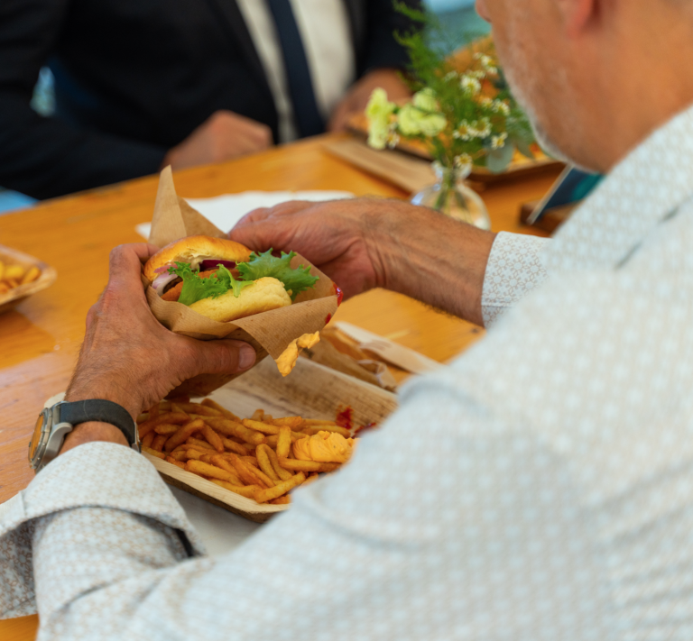 Gæst spiser burger og pommes frites ved bordet til et firmaarrangement
