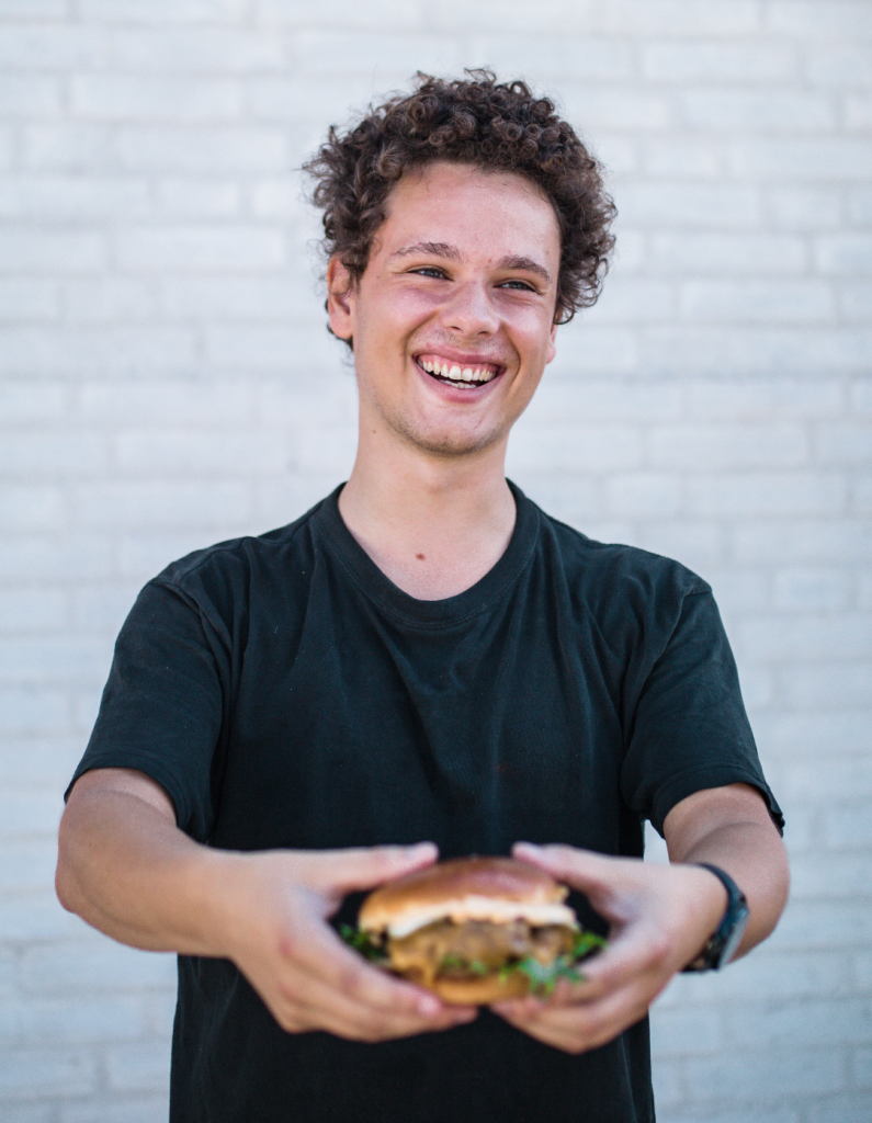 Smilende medarbejder fra Burger Foodtruck med en frisklavet burger